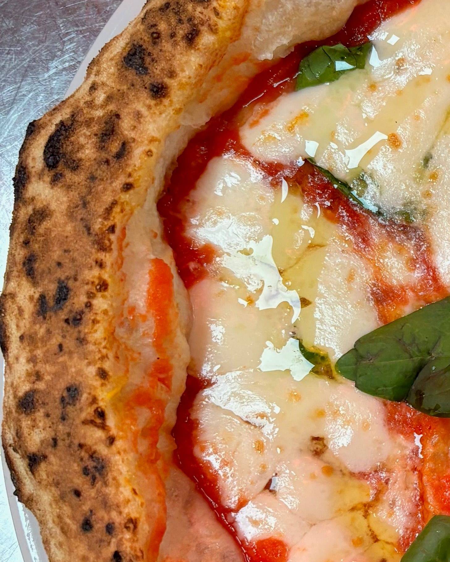 Détail d'une margherita : le bord de la pâte est marqué de petites taches sombres régulières.