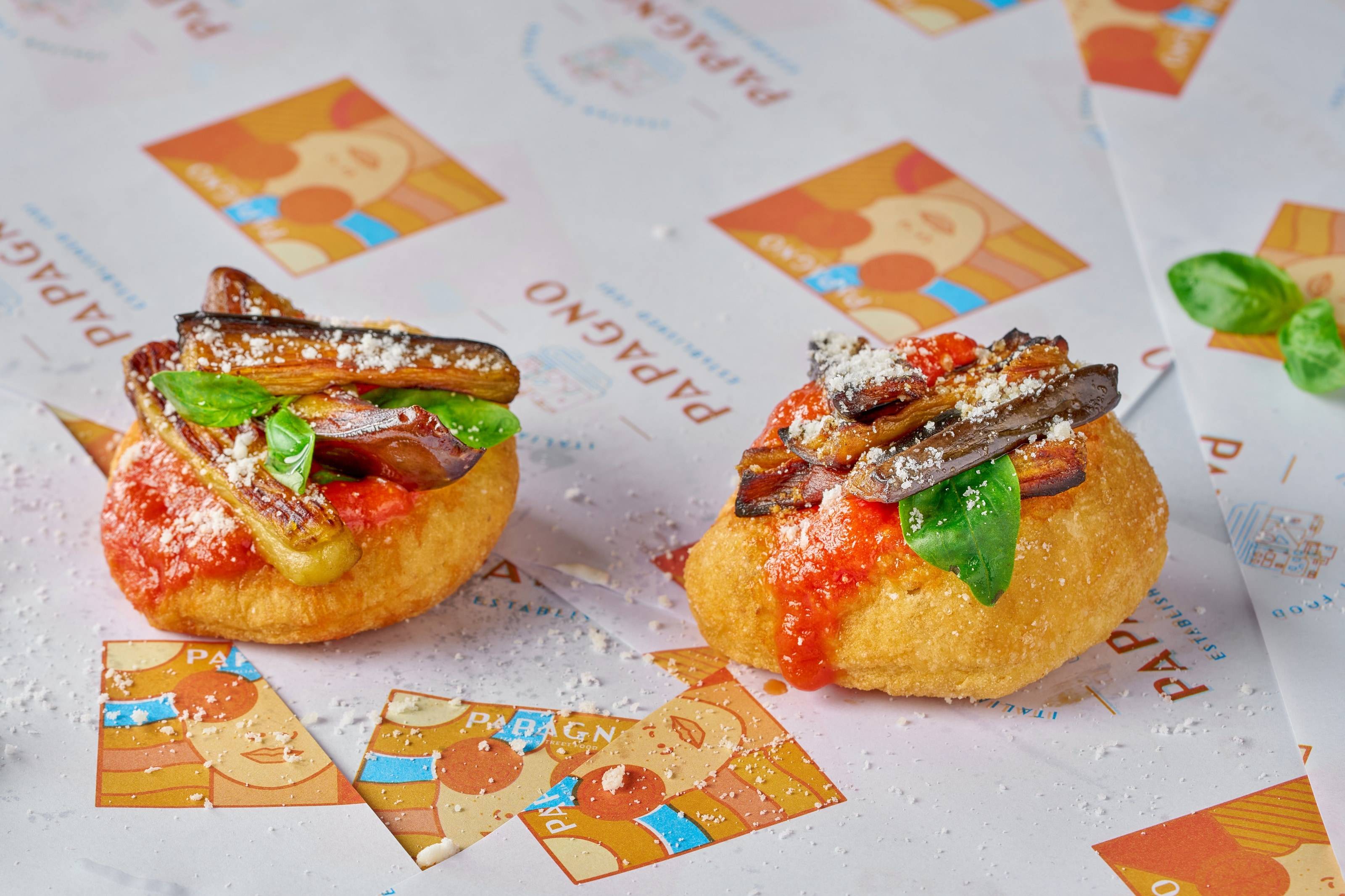 Deux petites pizzas frites garnies de sauce tomate, d'aubergines rôties, de fromage râpé et de basilic.