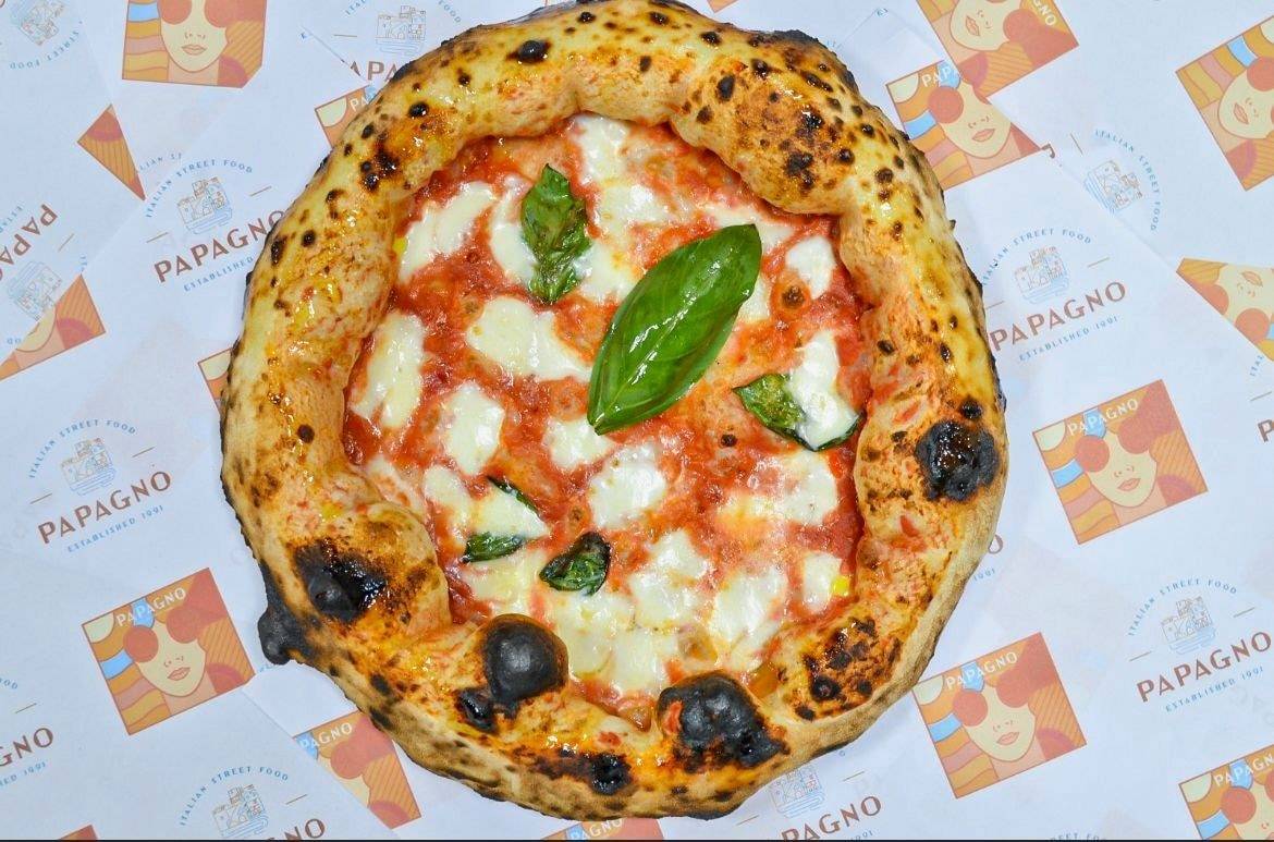 Pizza margherita posée sur le papier imprimé aux couleurs du projet Papagno.
